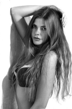 Siyah beyaz bir portre, açık arkaplanda uzun saçlı, seksi bir kız..