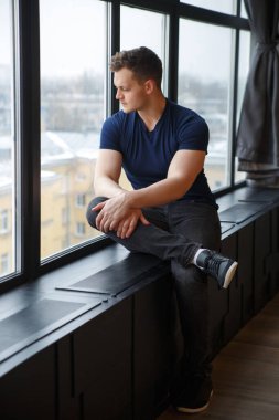 Tatlı, mutlu adam pencere eşiğinde oturuyor..