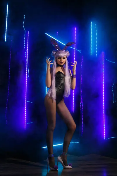 一个穿着性感兔子服装的纤细性感女舞蹈家在蓝灯和烟雾的映衬下茁壮成长 — 图库照片