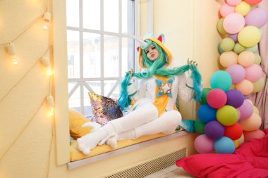 Tek boynuzlu at pijamalı tatlı bir kız pencerede oturuyor..