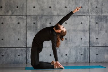 Genç sakallı bir adam spor salonunda yoga yapıyor..