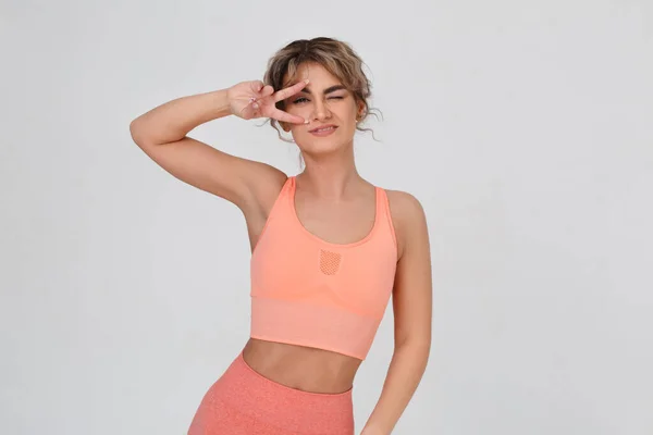 Slender Emotional Girl Pink Sportswear Looks Folded Fingers Victory Gesture — Stockfoto