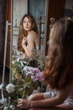 Cute beautiful girl is reflected in the morning mirror in the bedroom.