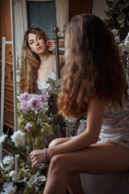 Cute beautiful girl is reflected in the morning mirror in the bedroom.
