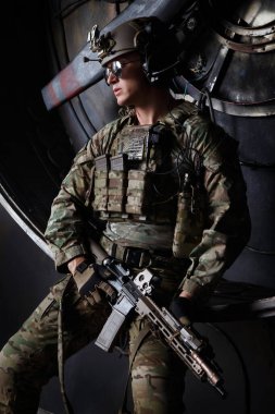 Kamuflaj üniformalı Amerikan askeri elinde makineli tüfekle endüstriyel bir arka planda..