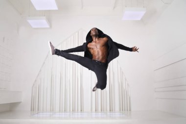 Siyah elbiseli zarif zenci dansçı parlak bir odada zıplıyor..