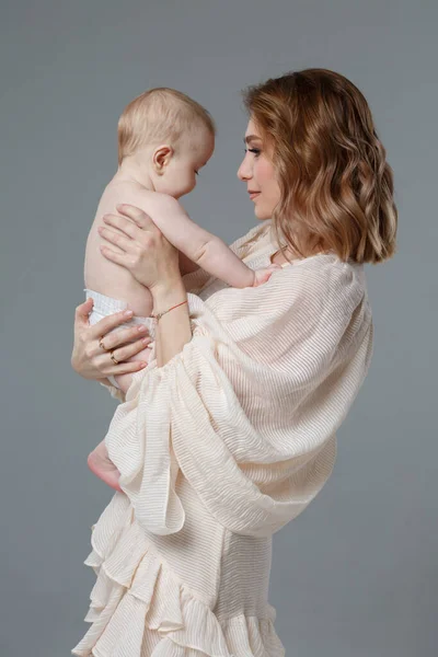妈妈把一个可爱的婴儿抱在怀里 与灰色背景隔离在一起 — 图库照片