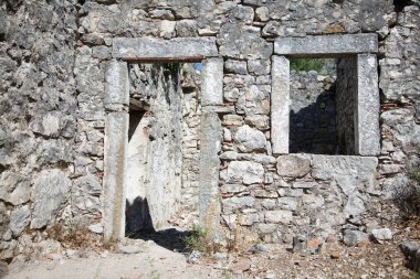 Pencereleri ve kapısı olan eski taş bir duvar..