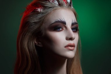 Yeşil arka planda yaratıcı makyajlı güzel bir kızın portresi..