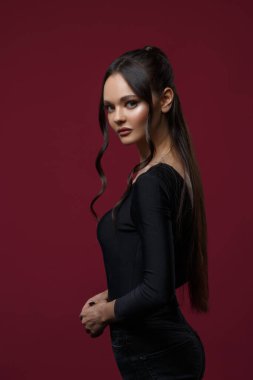 Siyah giyinmiş ince, güzel bir kız koyu pembe arka planda..