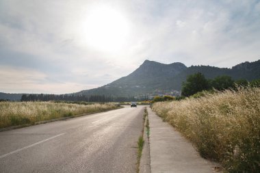 Alçak güneş ve yolu olan dağ manzarası.