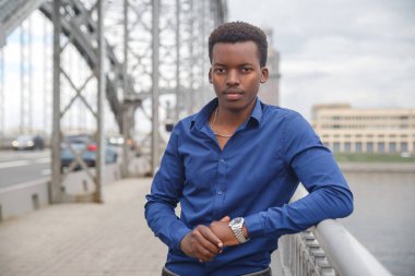 Şehirde bir köprüde, sıradan mavi gömlekli genç bir zenci..