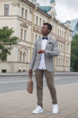 Klasik takım elbiseli siyah bir adam şehir caddesinde yürüyor..