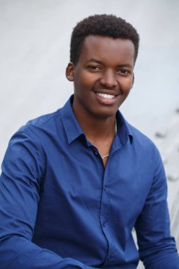 Neşeli, gülümseyen, çekici, mavi gömlekli siyah adam dışarıda..