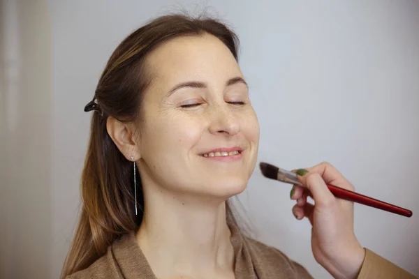 Maquillador Aplica Tono Cara Una Mujer Bonita Alegre Con Pincel —  Fotos de Stock