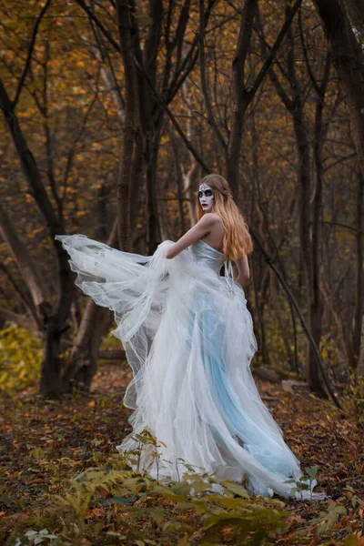 Yüzünde Korkunç Bir Makyajla Sonbahar Ormanında Uzun Beyaz Bir Elbiseyle — Stok fotoğraf