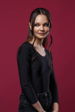 Siyah giyinmiş ince, güzel bir kız koyu pembe arka planda..