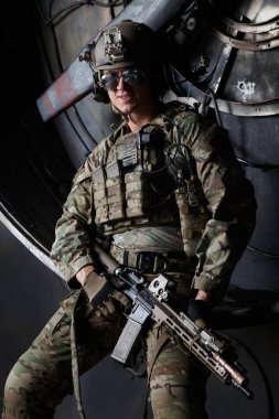 Kamuflaj üniformalı Amerikan askeri elinde makineli tüfekle endüstriyel bir arka planda..