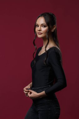 Siyah giyinmiş ince, güzel bir kız koyu pembe arka planda..