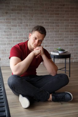 Burgonya giysili hoş bir adam kış günü panoramik bir pencerenin arkasında oturur..