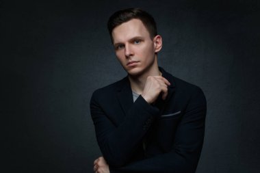 Siyah arka planda takım elbiseli yakışıklı bir iş adamının portresi..