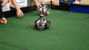 Gençler bloklardan yapılmış robotları test ediyorlar. Tekerlekli robot kendi ekseni etrafında döner. Robotik futbola hazırlanılıyor
