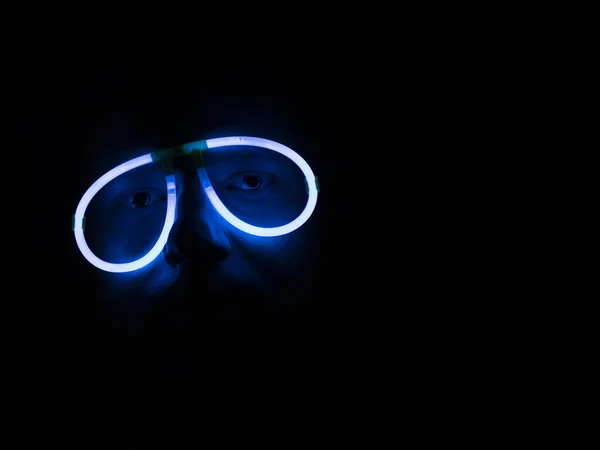 Karanlıkta komik floresan camlı adam. Neon gözlük çerçeveli kişinin garip silueti. Disko, parti, eğlence anlayışı