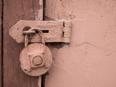 Ahşap kapıda asılı paslı pembe asma kilit. Kırsal, retro açılabilir kilit, kapat