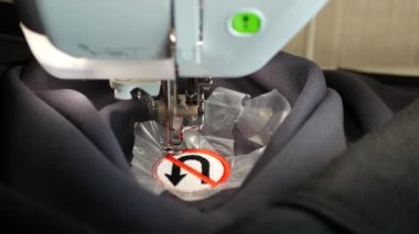 Nakış makinesi gri yün kumaş üzerinde geri dönüş levhası oluşturmuyor. Tekstil endüstrisi. İşlemeli U dönüşü trafik işareti yok