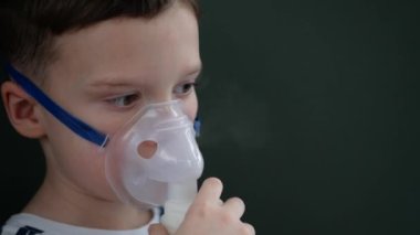 Çocuk nebulizör kullanarak nefes alıyor. Nebulizör maskeli küçük çocuk koyu yeşil bir arka plana yaklaş.