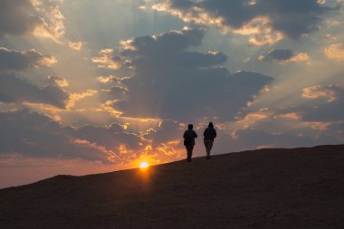 Damaraland 'da güzel bir gün doğumu. Taş bir tepede yürüyen tesadüfi insanlar. Namibya. Afrika