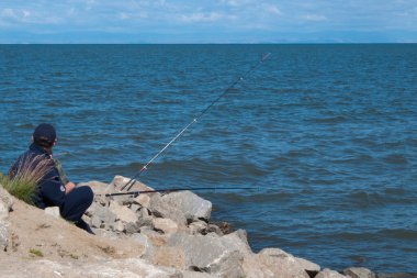 Baykal gölünde balık tutan tanınmamış bir adam. Sırtından görüldü. - Rusya. Baykal Gölü, dünyanın kabuğunun yavaşça parçalandığı Baykal Yarık Bölgesi tarafından oluşturulan bir yarık vadisinde. 636 km (395 mi) uzunluğunda ve 79 km (49 mi) genişliğindeki Baykal Gölü, 