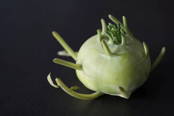 Close up of a green kohlrabi with its strange tentacles. Black background. Spain