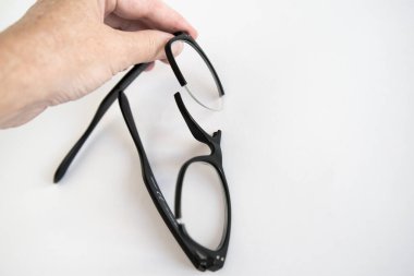 Kırık gözlük çerçevesi tutan tanınmayan bir insan eli. Beyaz arkaplan