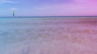 Yelkenli denizin ortasında yüzüyordu ve dalgalar kıyıya doğru ilerlemeye devam ediyordu..