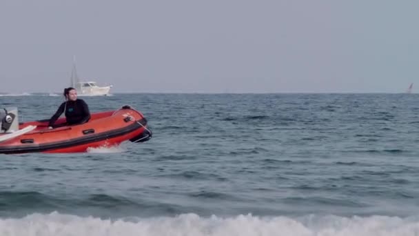 Şişme motorlu yat. İki adam denizde ışık dalgalarıyla yol alıyor.. — Stok video