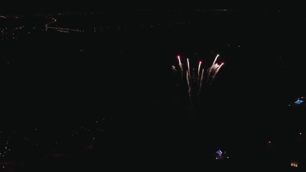 Bright colorful firework bursts in night sky above city. — Stock Video