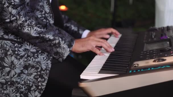 Мужчина играет на фортепиано, а музыканты поют на сцене вечером — стоковое видео