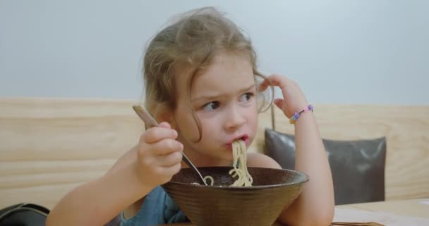 Söt liten blond flicka försöker äta med pinnar i orientalisk restaurang. — Stockvideo