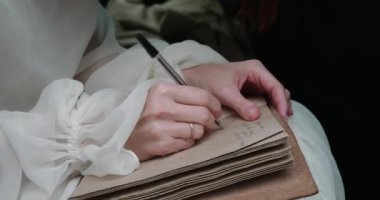 Gelinlik giymiş genç bir kadın arabada mektup yazıyor.
