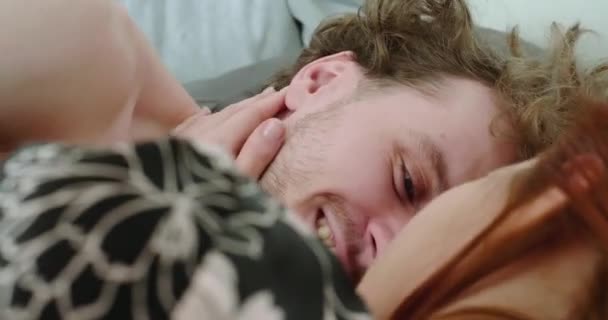 Mannen tittar på en kvinna, liggande i sängen på morgonen nära utsikt. — Stockvideo