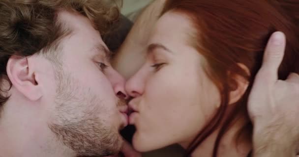 Kvinna kysser en man, liggande i sängen på morgonen nära utsikt. — Stockvideo
