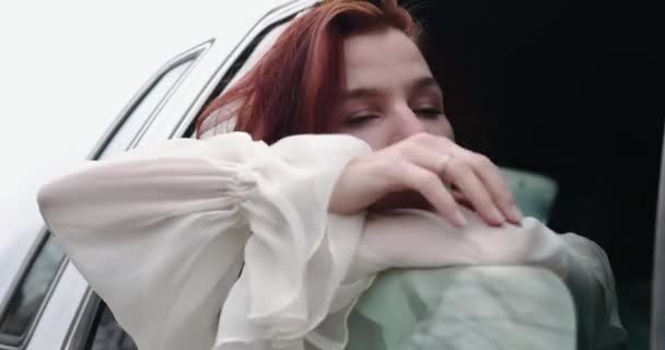 Jonge vrouw kijkt uit het raam van een retro auto zittend op de achterbank — Stockvideo