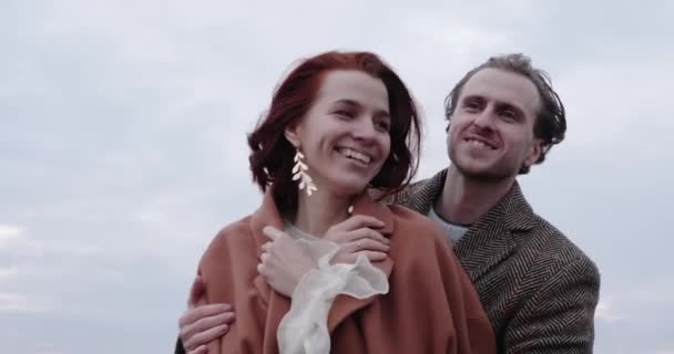 Lycklig man och kvinna kramas och ler på vild äng vid solnedgången — Stockvideo