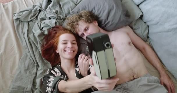 Jong getrouwd stel lachen en neemt een selfie op een vintage camera in de ochtend — Stockvideo