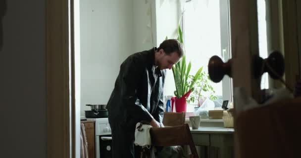 Fiatalember, egy táskát gyűjt a konyhában, mielőtt elhagyja a házat. — Stock videók