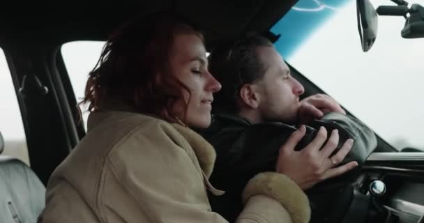 Młoda szczęśliwa para siedzi w samochodzie przytulając się i uśmiechając zbliżenie — Wideo stockowe
