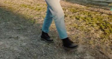 Gün batımında çimenlerde yürüyen çizmeli bir kadının ayakları..