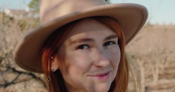 Redhead woman in stylish hat fixes hair looking in camera — Vídeo de Stock