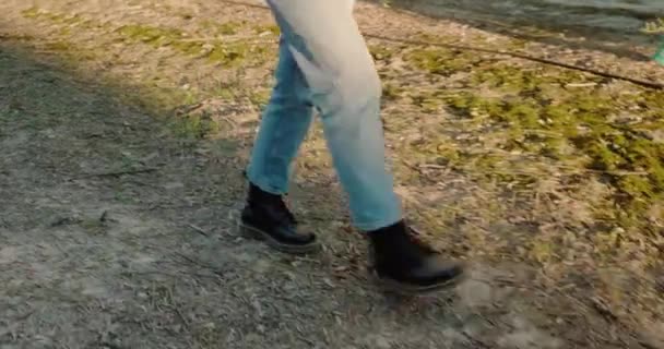 Feet of a woman in boots walking on dry grass, at sunset. — Vídeo de Stock